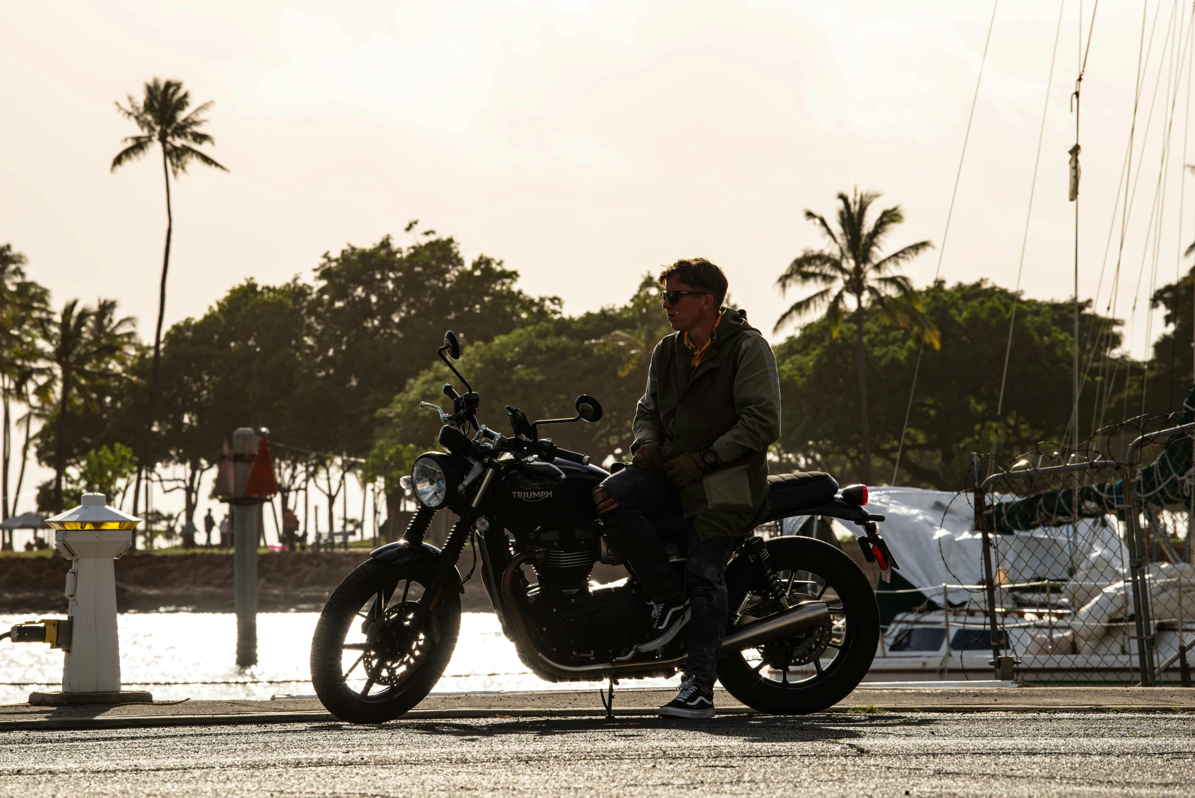 a man in sunglasses sits on his motorcycle near the water