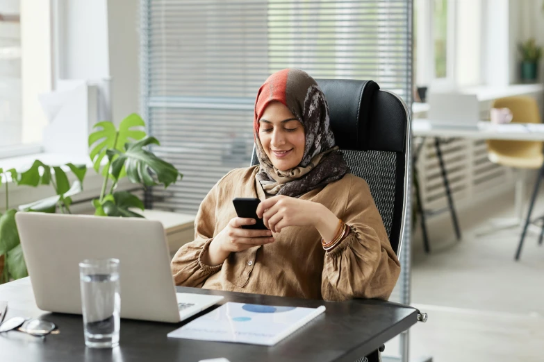 woman sitting in office chair, using cell phone