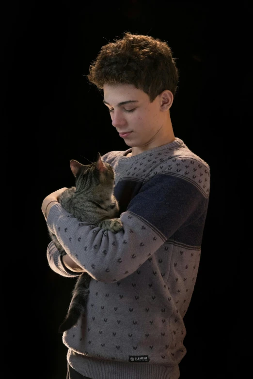 a young man holding a cat in his arms
