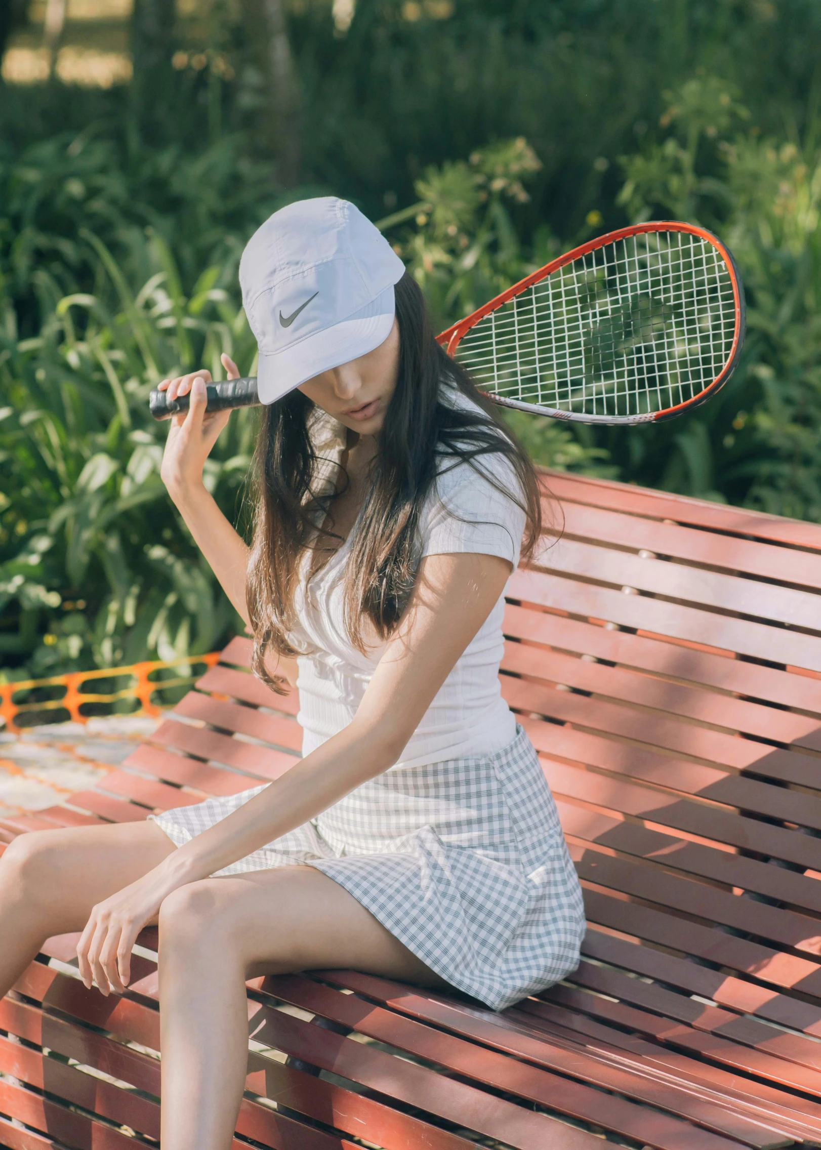 a woman holding a tennis racquet while sitting on a bench