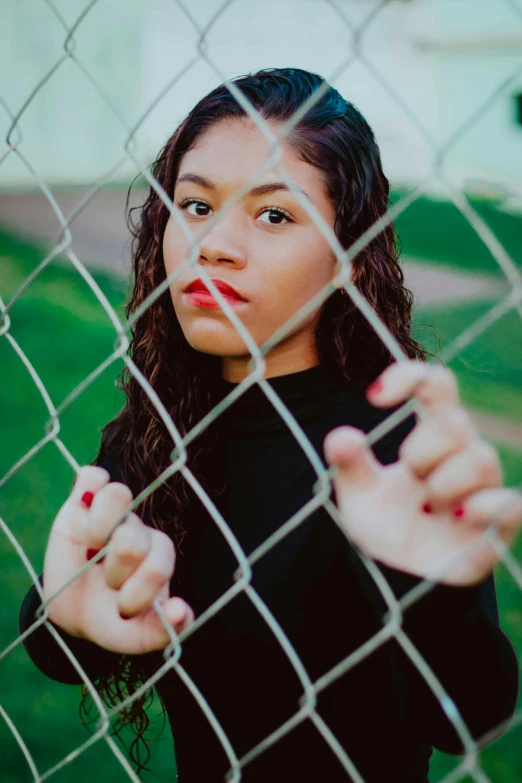 a girl behind a fence with her hand in front of the camera