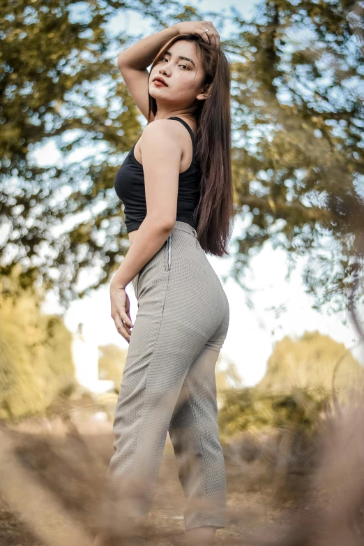 a young woman is standing in the middle of a field with her arms behind her head