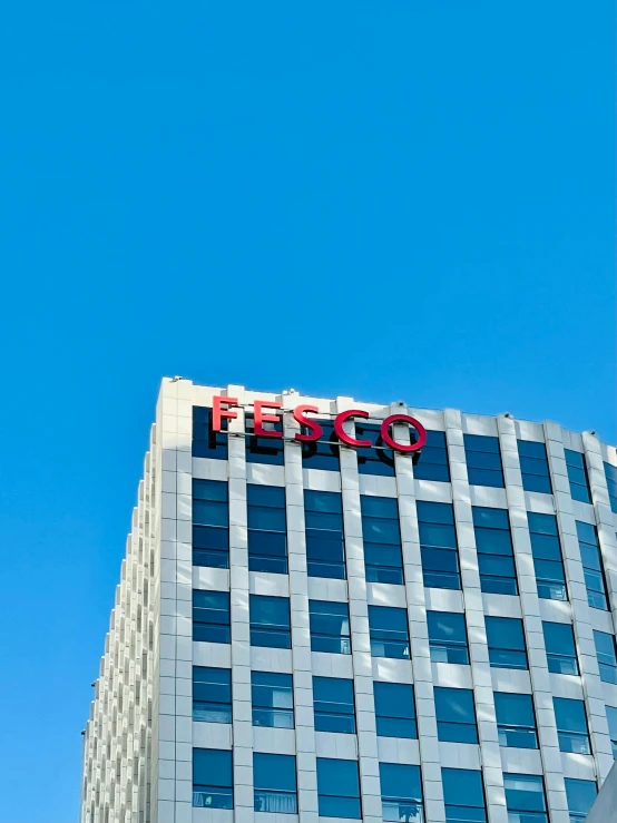 the side of a tall white and grey building with a sign for the company