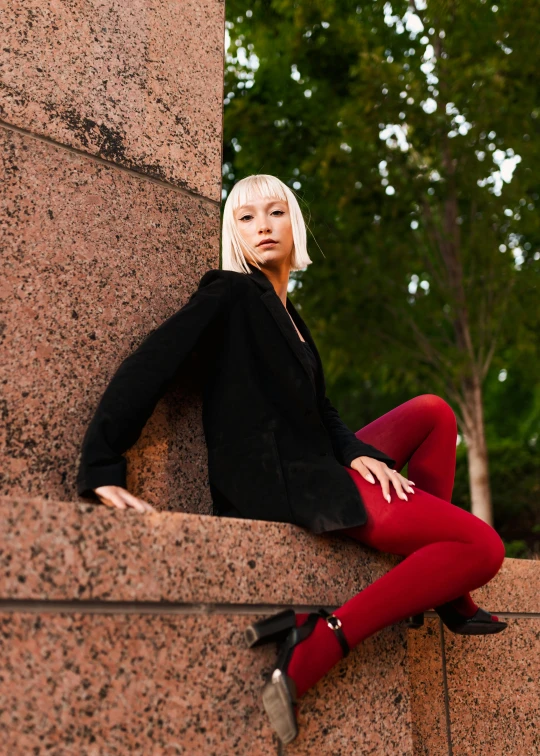 woman in black jacket and red pants posing at the corner