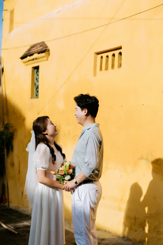 two people standing next to each other holding flowers