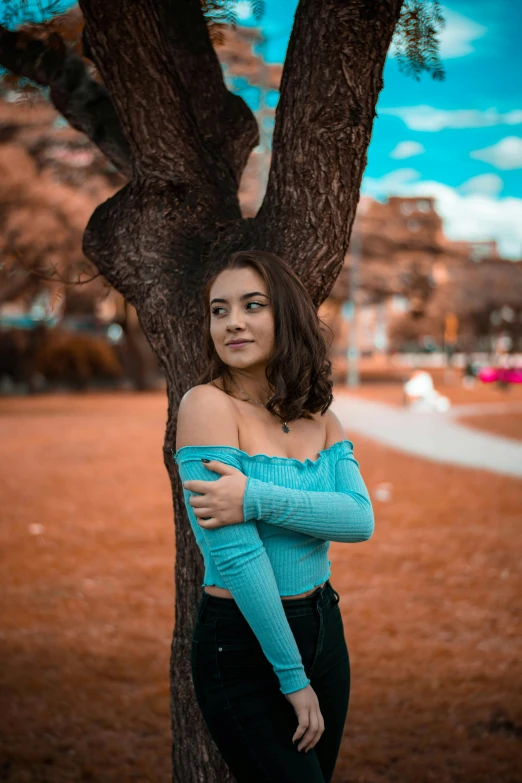 the woman is posing by a tree for a picture