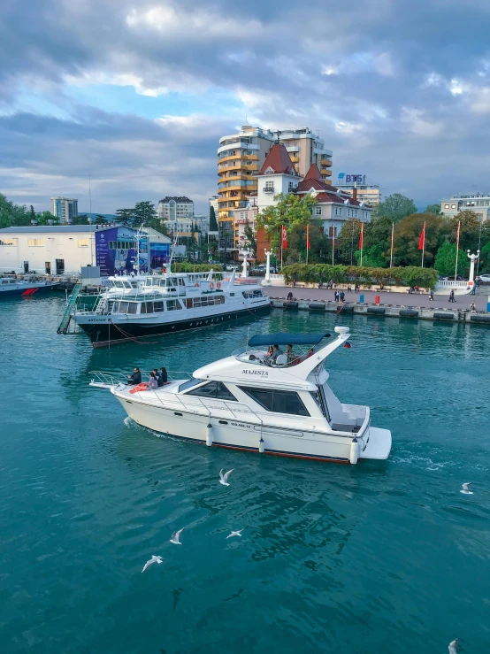 an ocean area that has a small white boat in the water and several larger boats floating along side each other