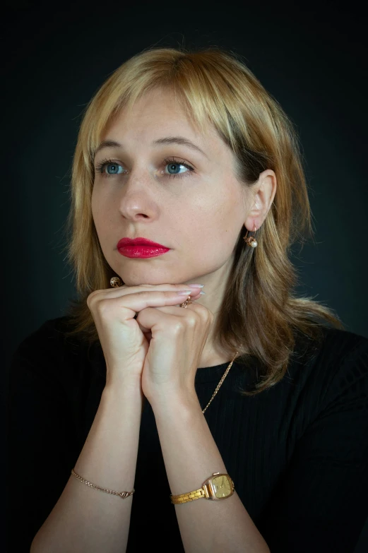 woman with blue eyes wearing gold necklace and celet with black background