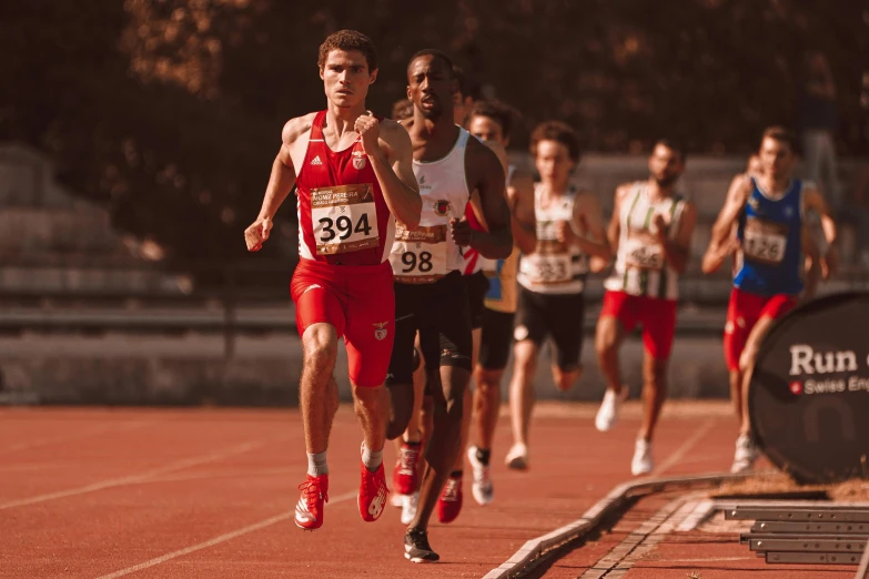 a group of men are running on a red track