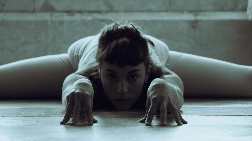 a woman stretches with one leg forward on the floor