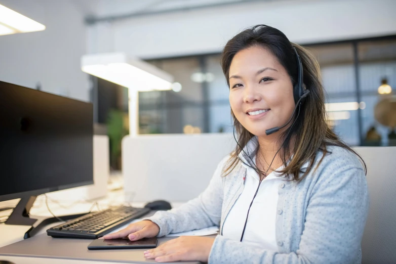 a woman sitting at a computer desk with a headset