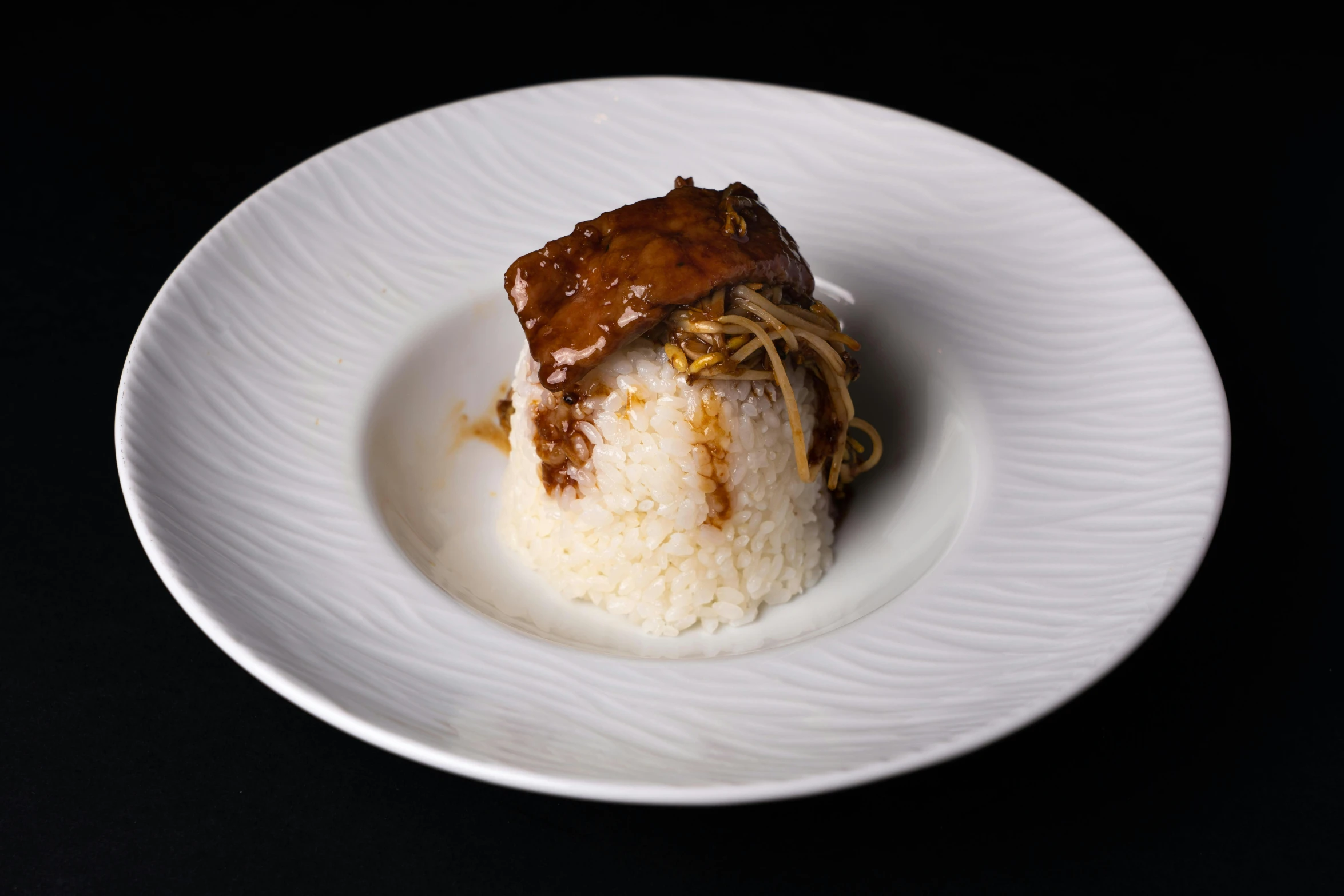 a dish on a black table holding noodles and meat