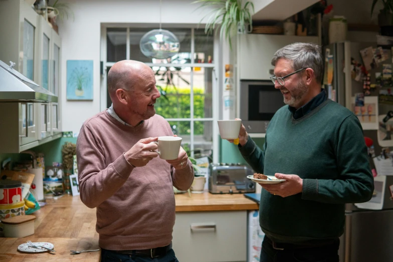 two men are eating in the kitchen together