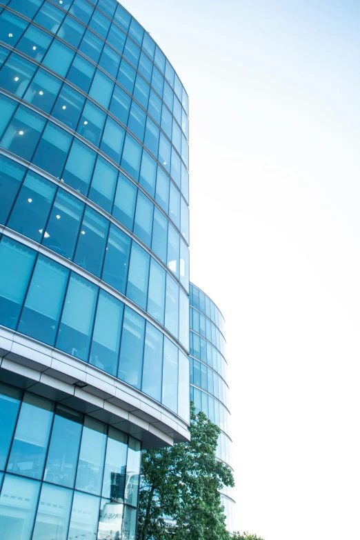 a tall blue glass building is shown against a clear sky