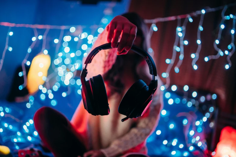 a man wearing headphones sitting on the ground in front of a christmas light