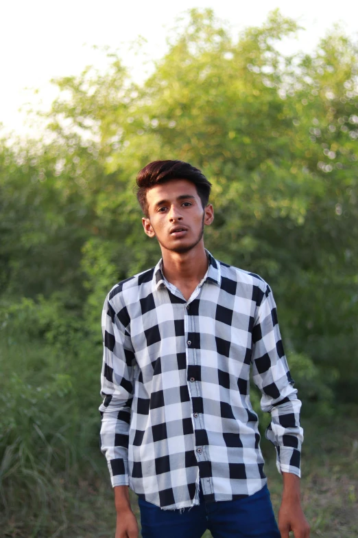 a man in a checkered shirt poses for the camera