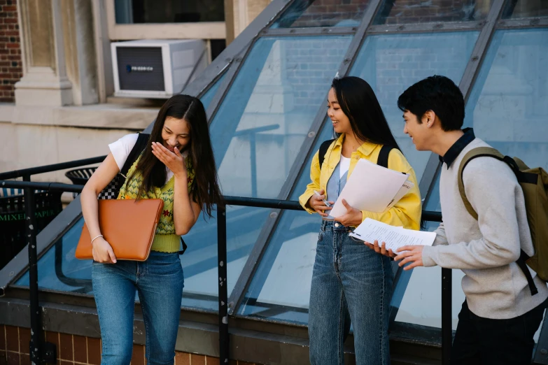 two s looking at an apartment building while another student holds his book