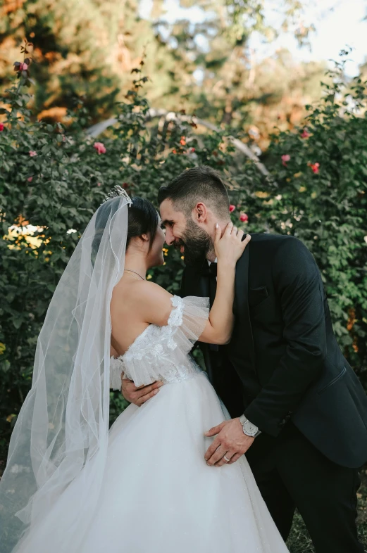 bride and groom emcing outside in front of roses