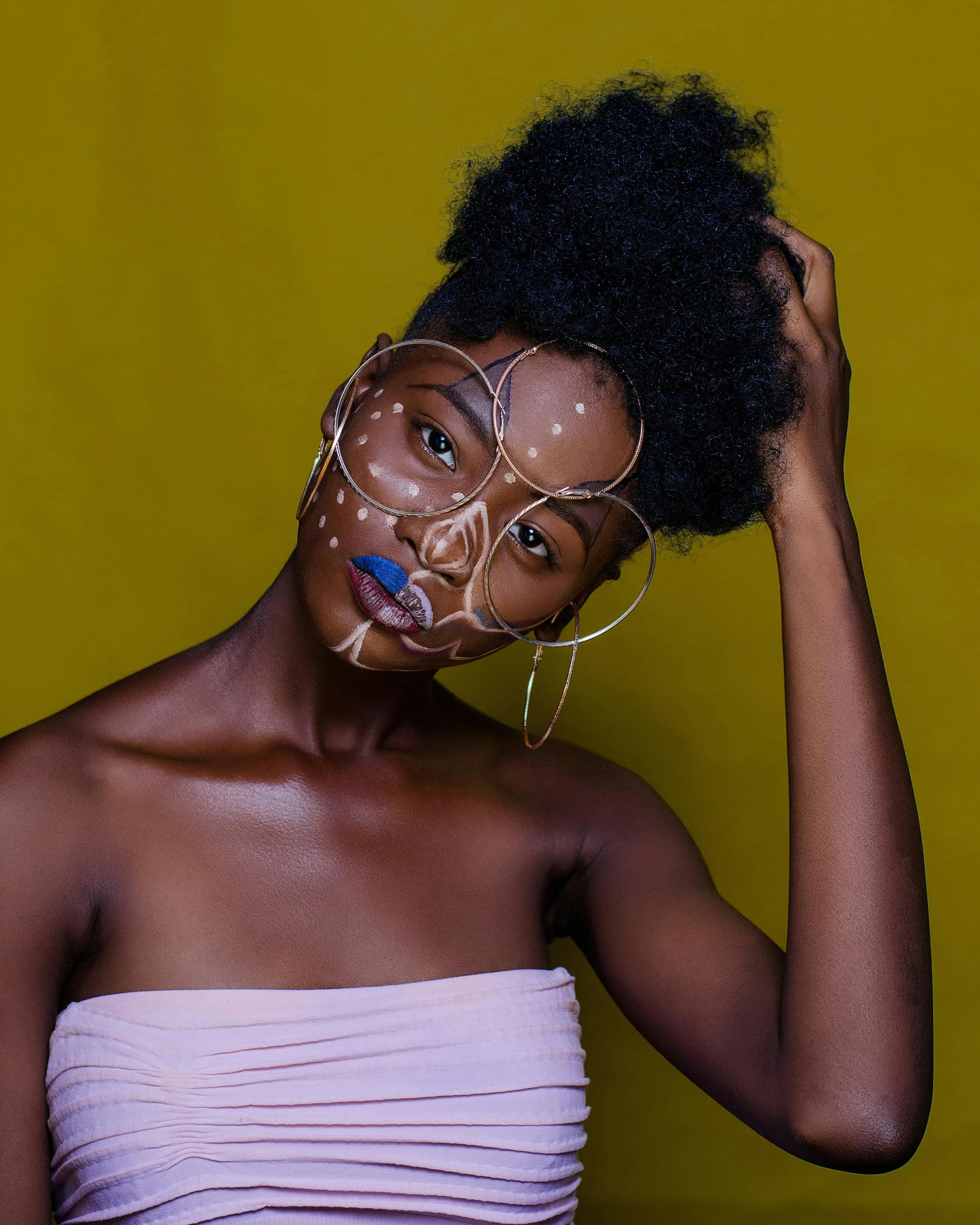 woman with african face painting standing in front of a yellow wall