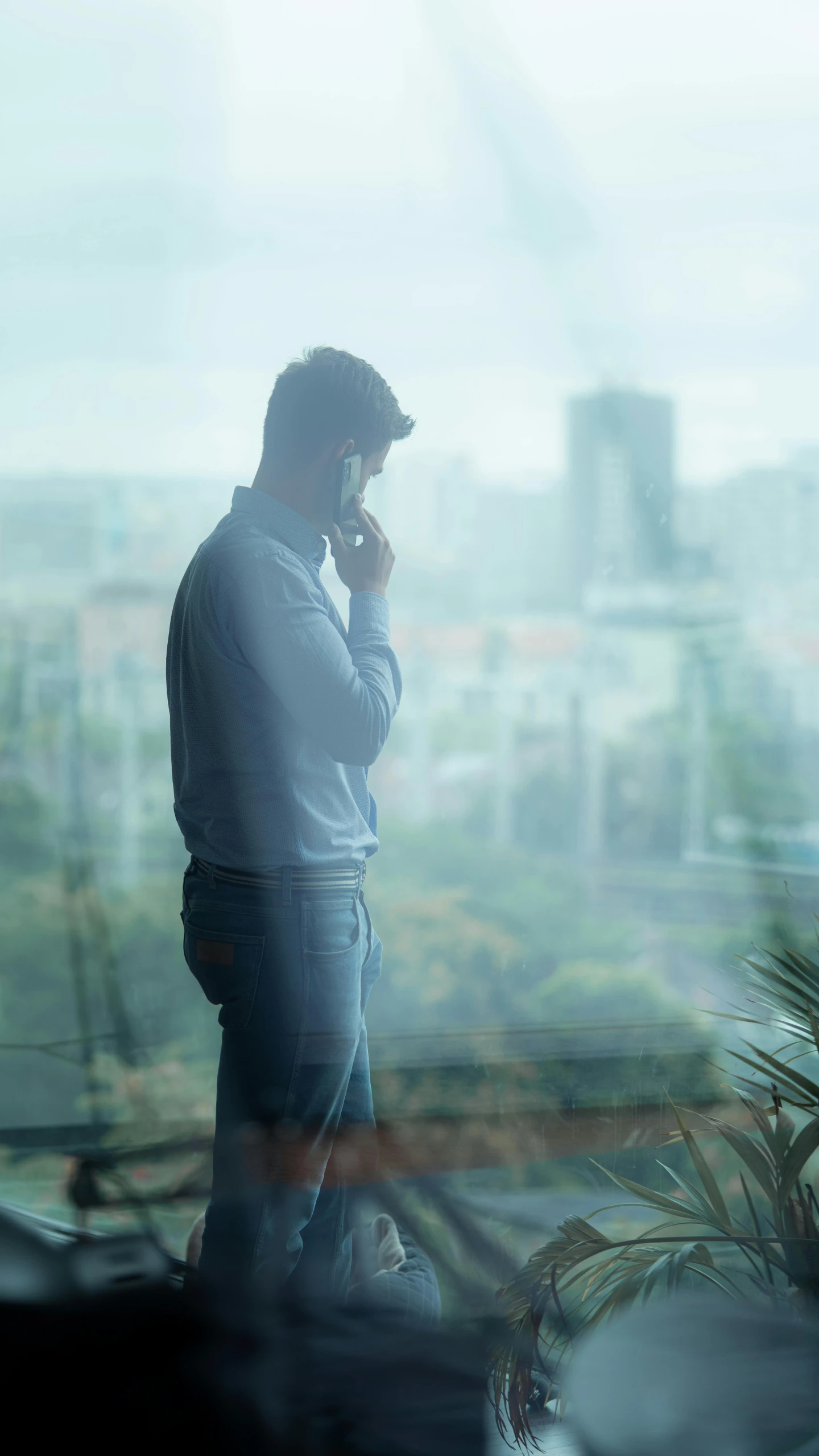 a man standing in front of a window talking on a cell phone