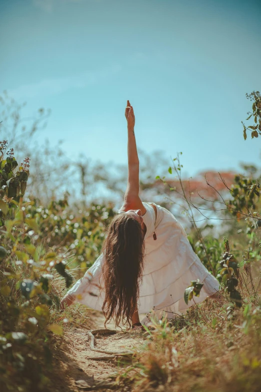 a woman is standing in a field holding her arms up