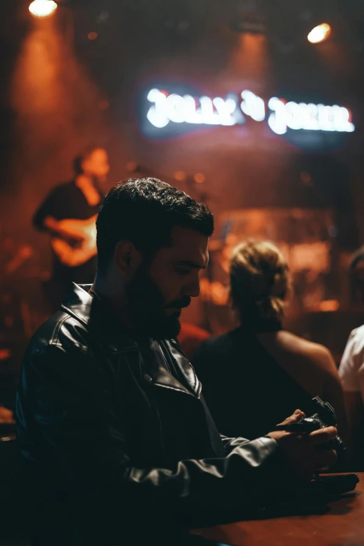 a man in a leather jacket sitting at a bar