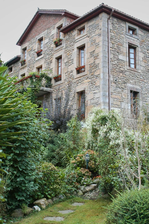 a stone building is surrounded by flowers and greenery