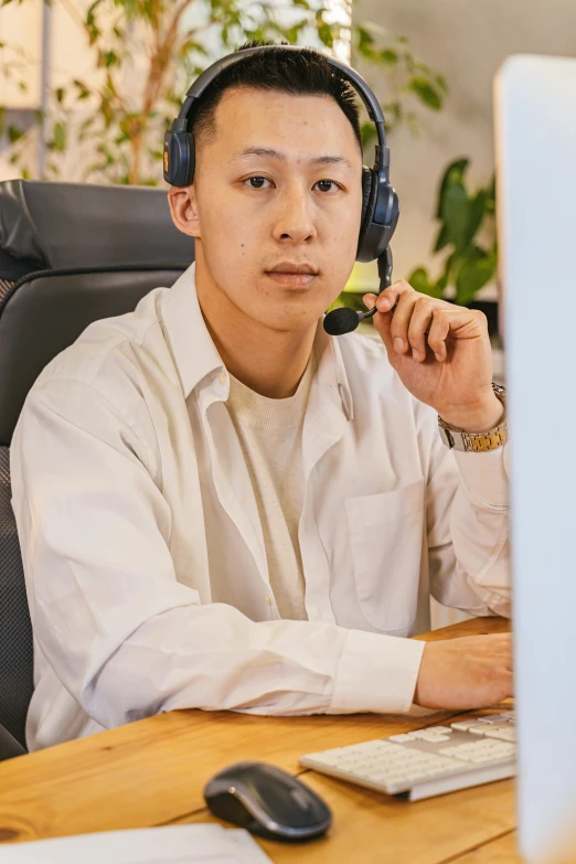 the man in the shirt is wearing headphones and using his computer