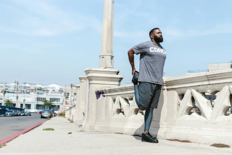 a man with a gray shirt stands next to a statue