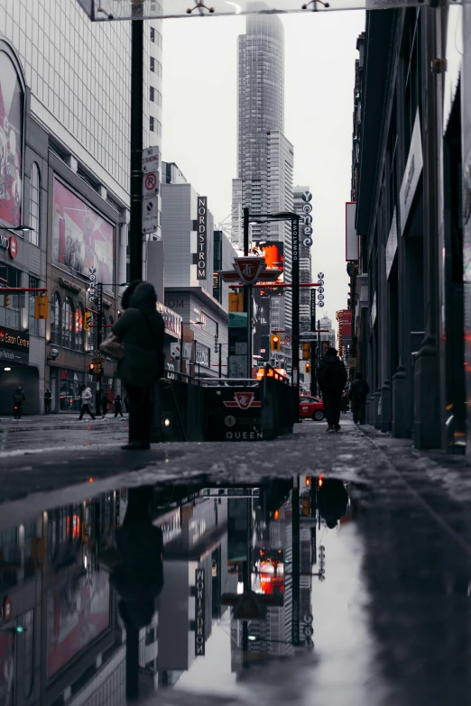 people walking in the rain next to a water dle