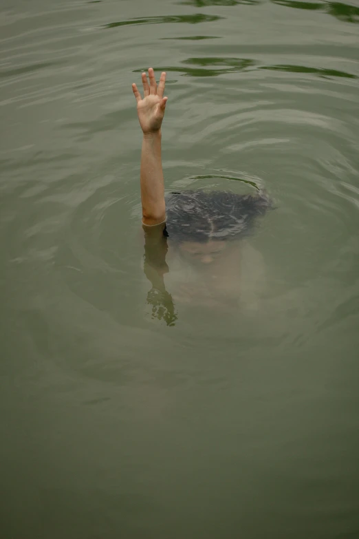 the hand reaches out from under the water to touch the surface