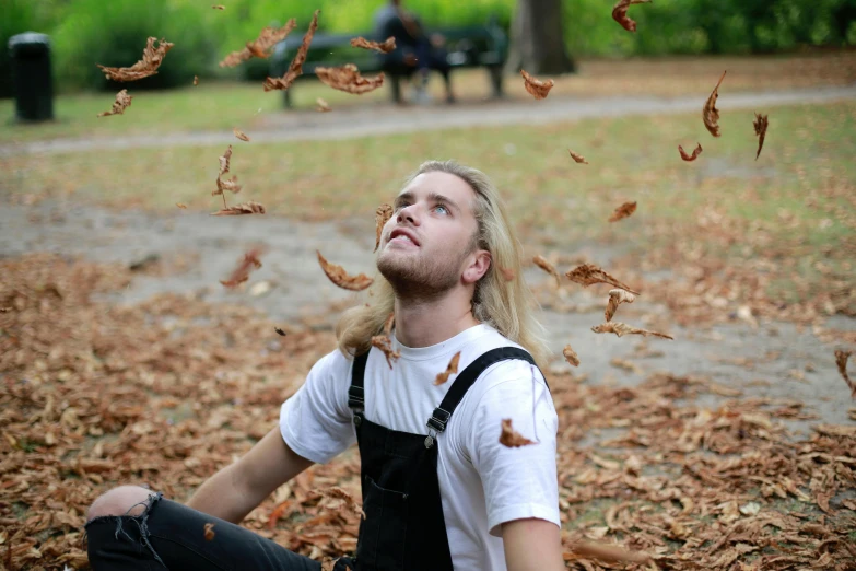 the man is sitting on the ground near leaves