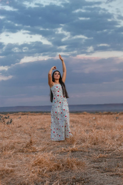 a woman in a field with her arms up in the air