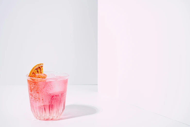 a pink cocktail is on the side of a white wall