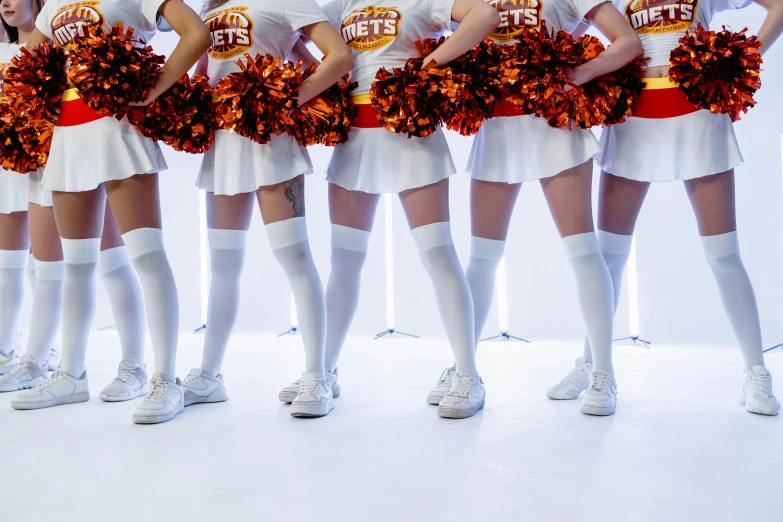 four cheerleaders in various orange and white outfits