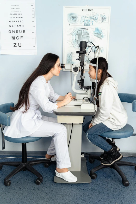 two women sitting at a desk looking at the microscope