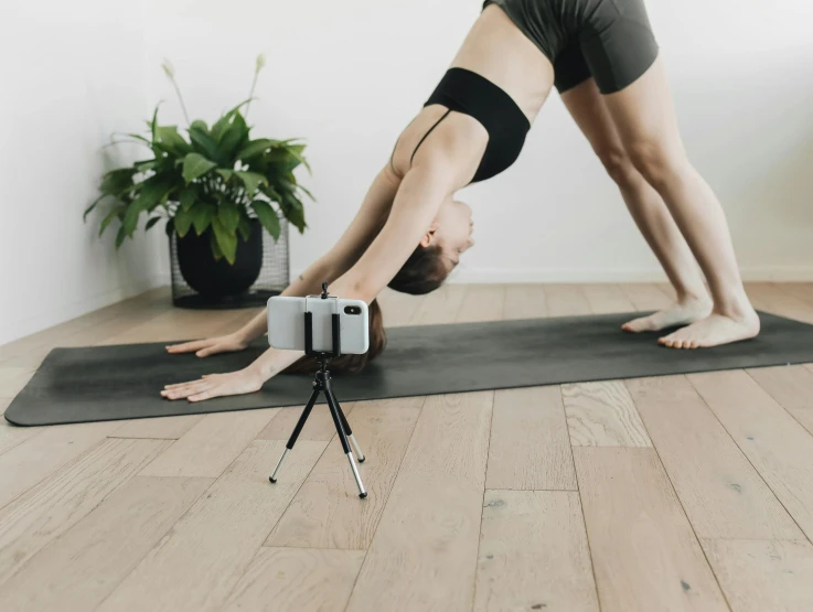 a woman standing on her legs doing a downward handstand pose