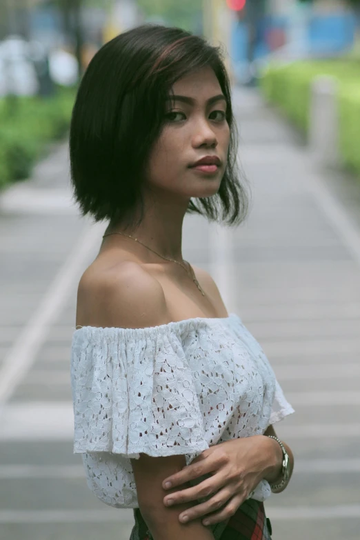 the woman is posing on the street near a brick wall