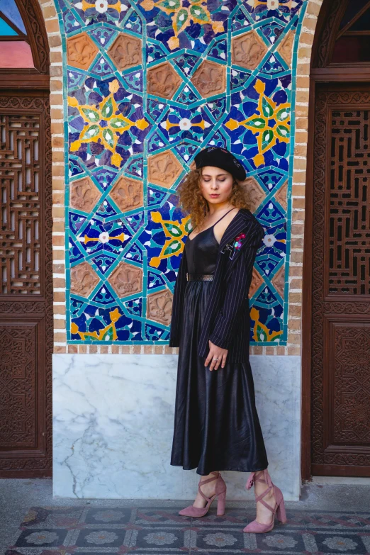 a  poses in front of an ornate wall