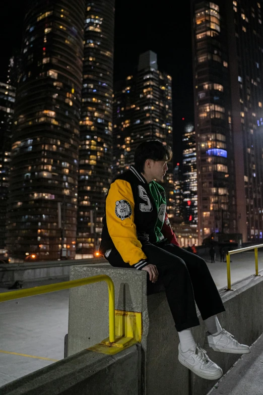 a person sitting on a railing in front of a night cityscape