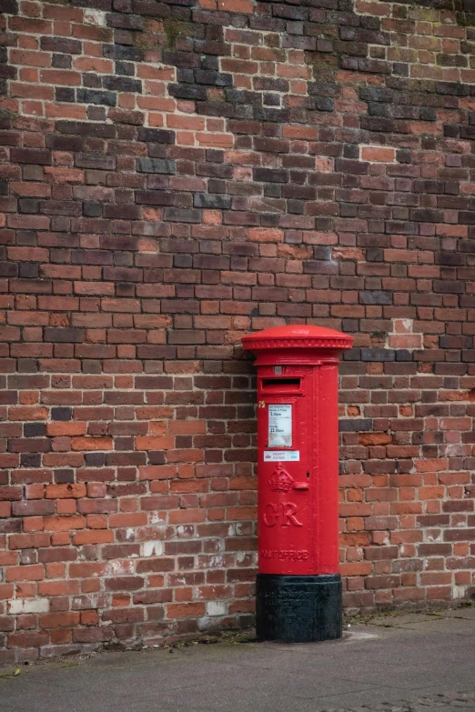 a large red pillar on a brick wall next to a sidewalk