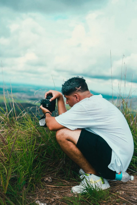 man taking picture on camera with the view of the valley