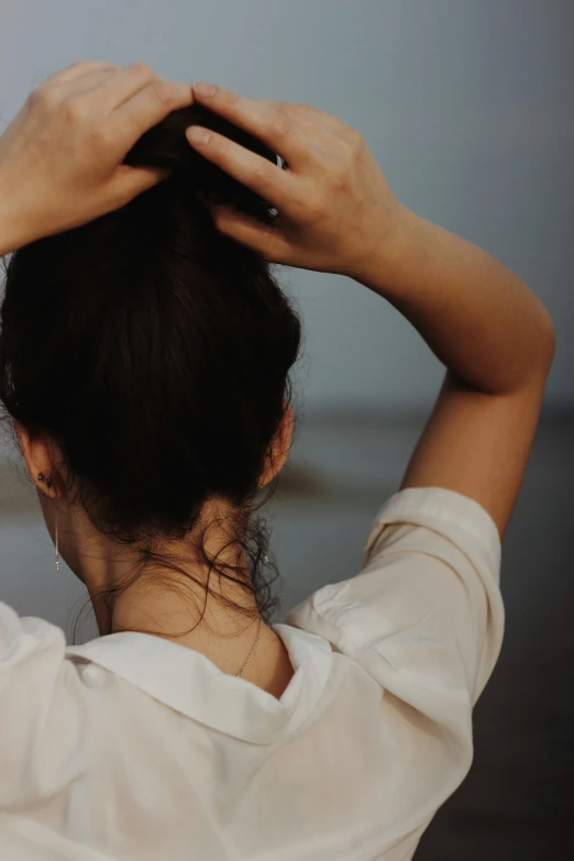 the woman is putting her hair back by her hands