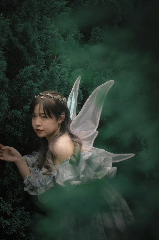 the fairy is standing outside next to a lush green forest