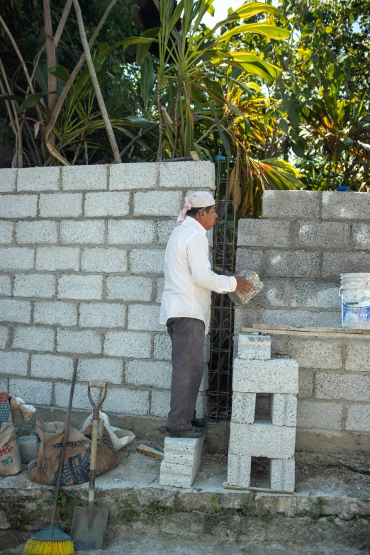 a man putting concrete in a cinder block wall