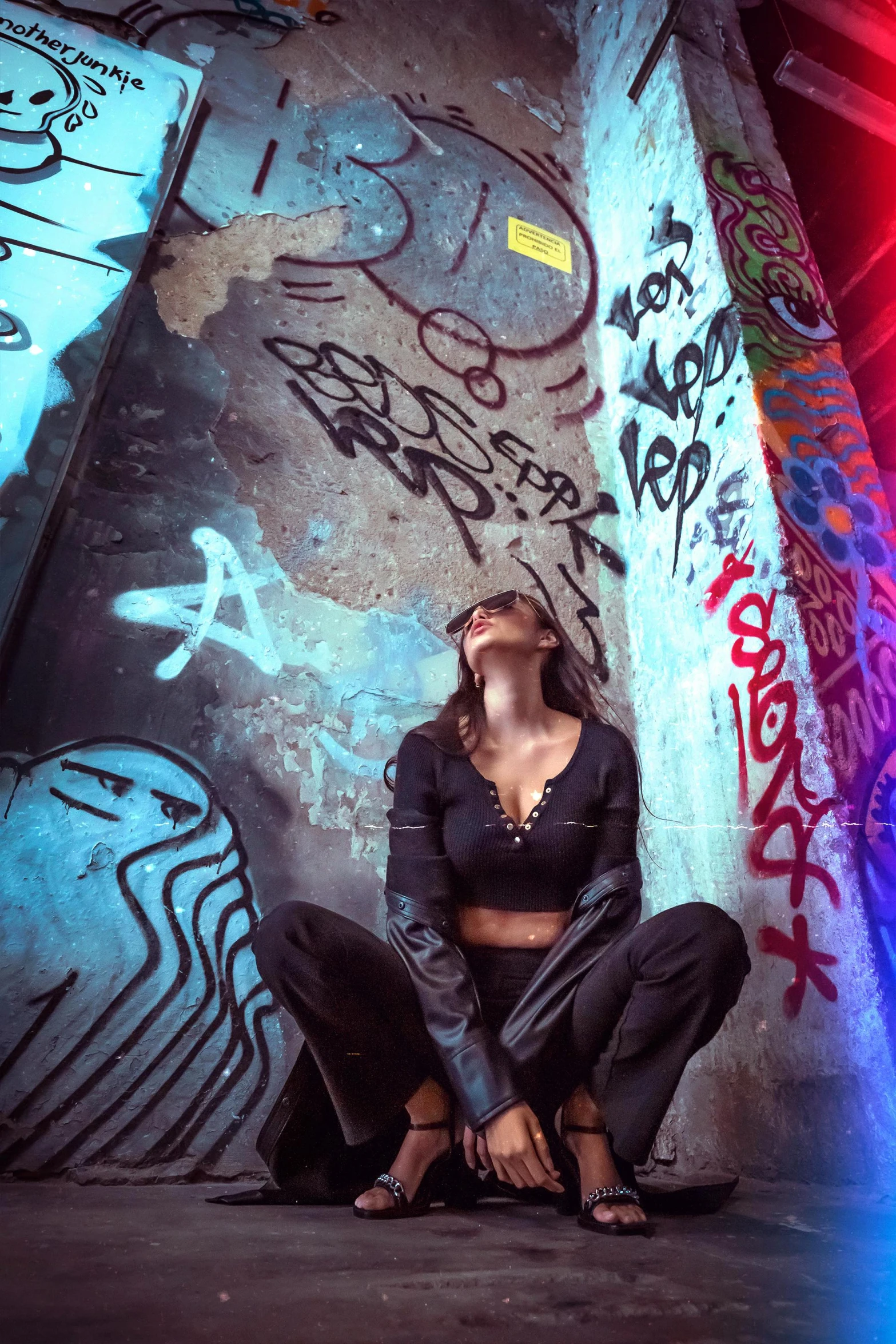 a young woman sits on the ground near graffiti