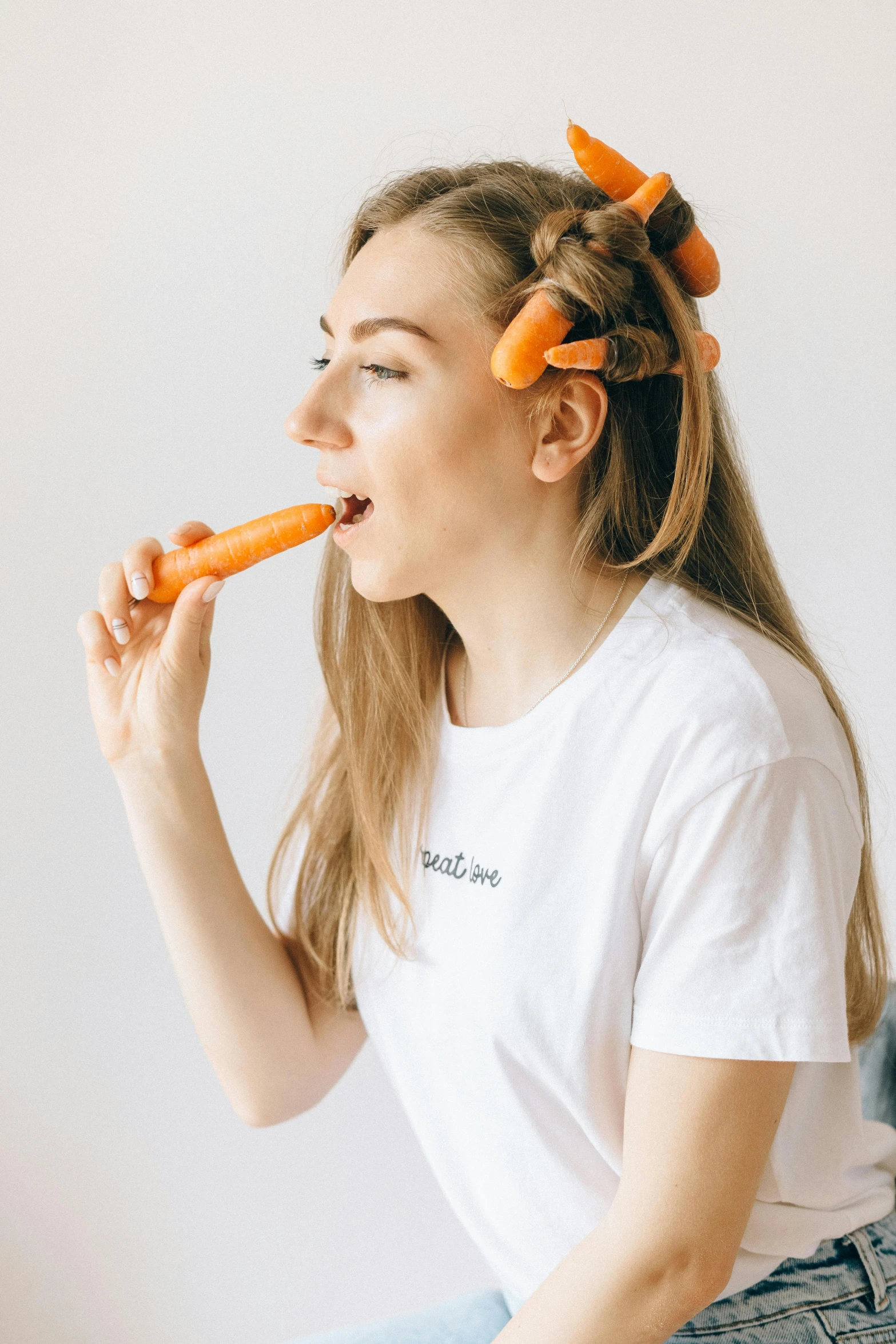 a girl with orange fake hair is eating a carrot