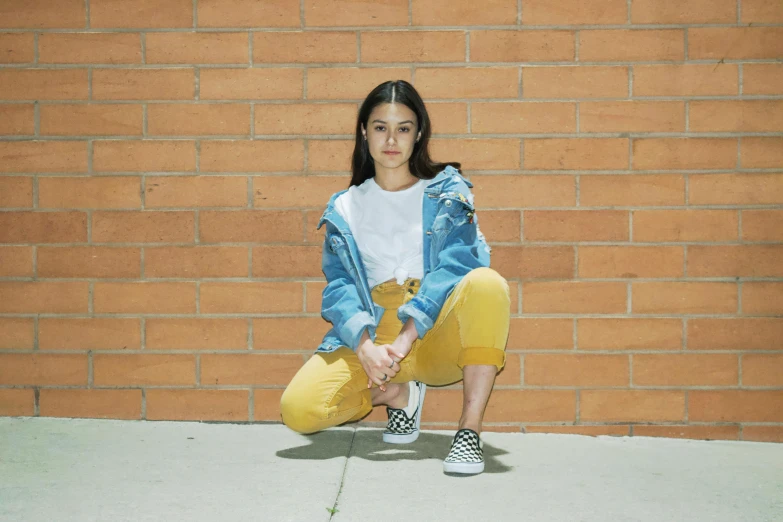 a woman sitting against a brick wall posing