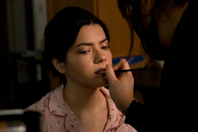 a woman getting her lip brushed by another lady