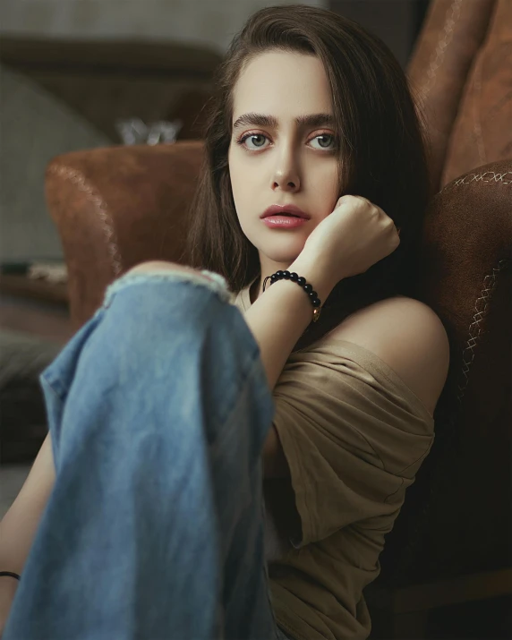 young woman resting on arm chair, looking away from camera